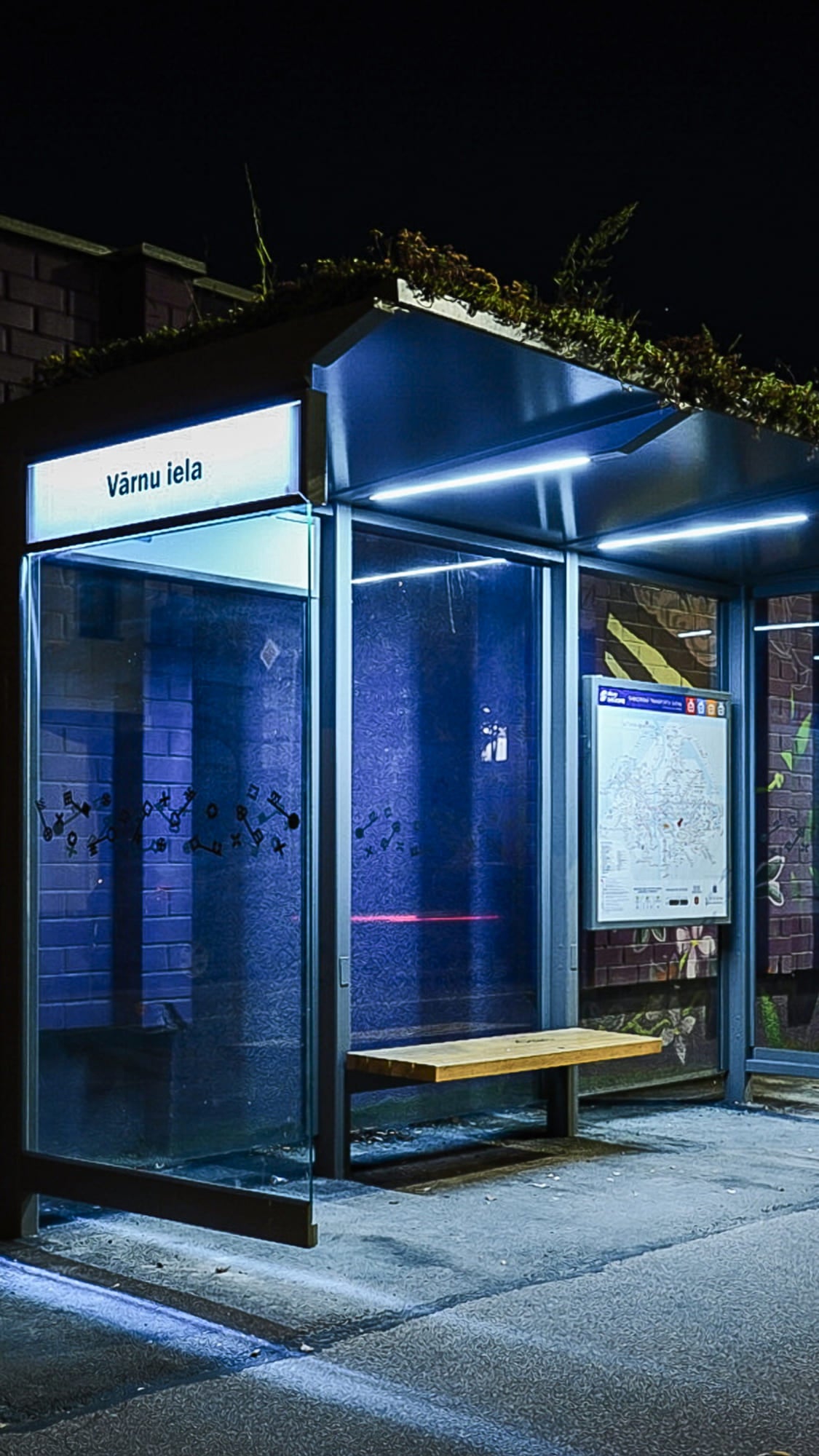 Modern glass bus stop with bench at night